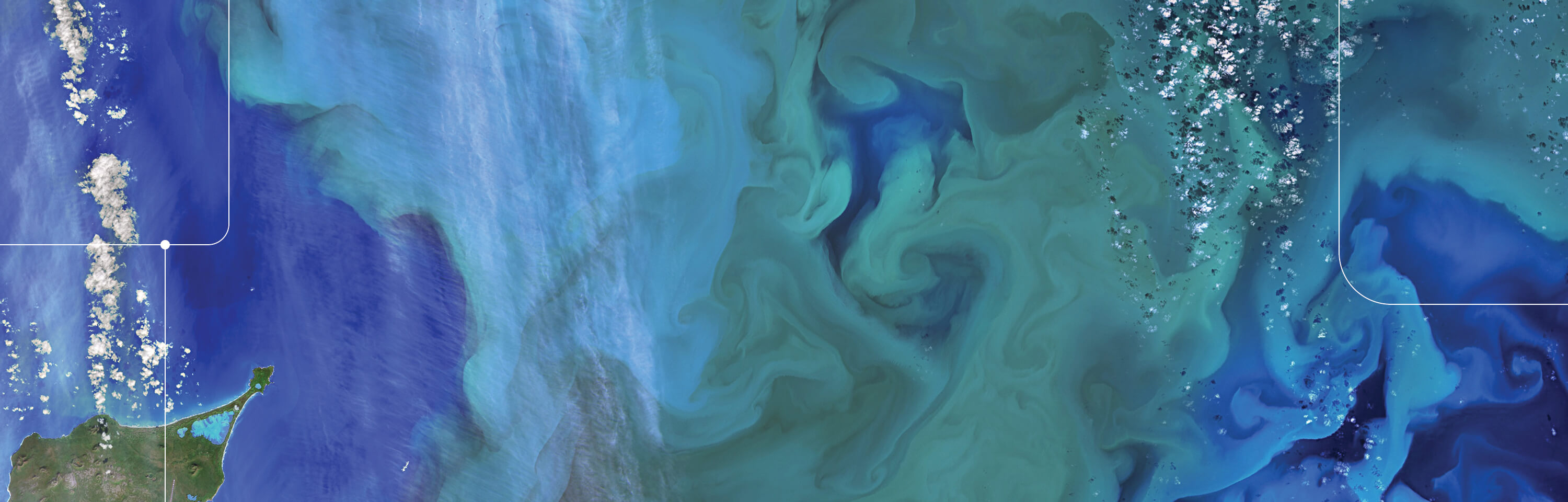 Satellite view of topography of land and blue/teal swirling water, dappled with clouds
