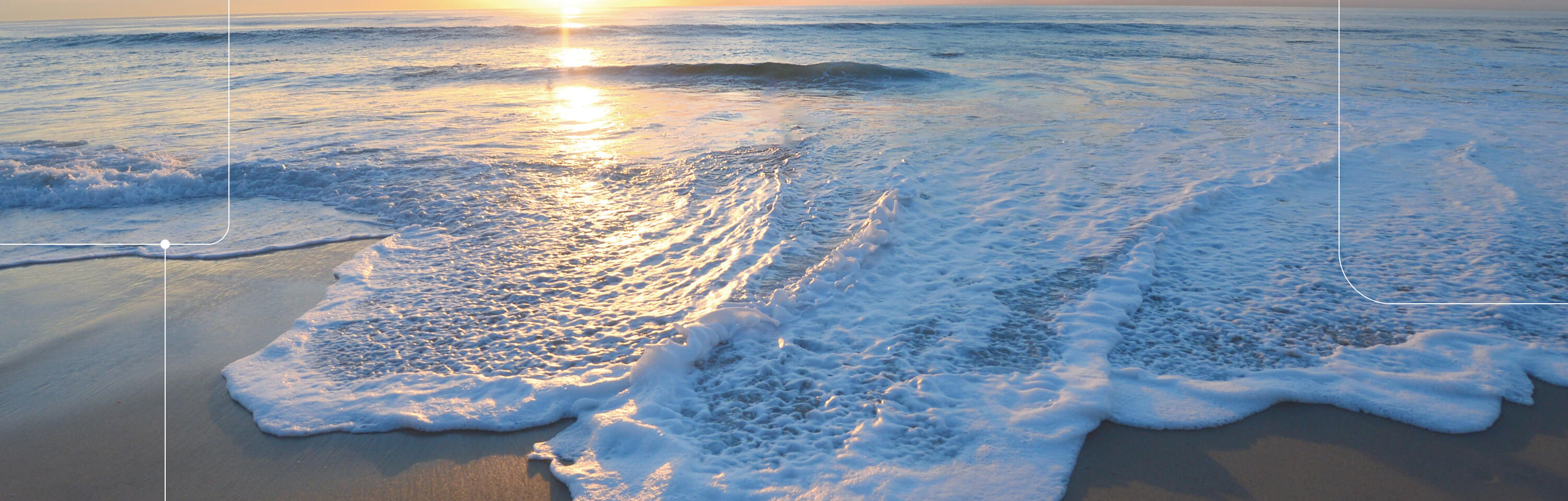 Ocean waves washing up on the shore in La Jolla, view looking out to the ocean with the sun on the horizon