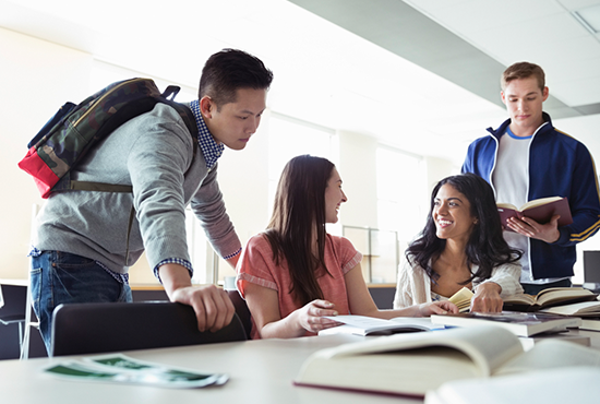 Stock image of students around a desk discussing a work